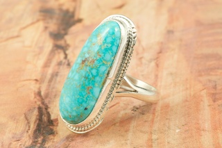 Genuine High Grade Kingman Web Turquoise set in Sterling Silver Ring. Created by Navajo Artist Larson Lee. Signed by the artist. The Mineral Park Mine, in the Cerbat Mountains 14 miles northwest of Kingman, was first mined by Indians centuries before white man came to the area.  It is one of the three sites of prehistoric mining localities in the state of Arizona.  Mineral Park was the most extensively worked area by the Indians of the three.  S.A. �Chuck� Colbaugh  found a cache of stone hammers uncovered in ancient trenches and tunnels, when he had the turquoise mining concession in May of 1962.  Ithaca Peak and Turquoise Mine (formally called Aztec Mountain or Aztec Peak) are the most famous of the peaks in the area containing turquoise. 
